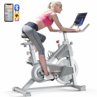 Woman using a stationary exercise bike with a tablet.