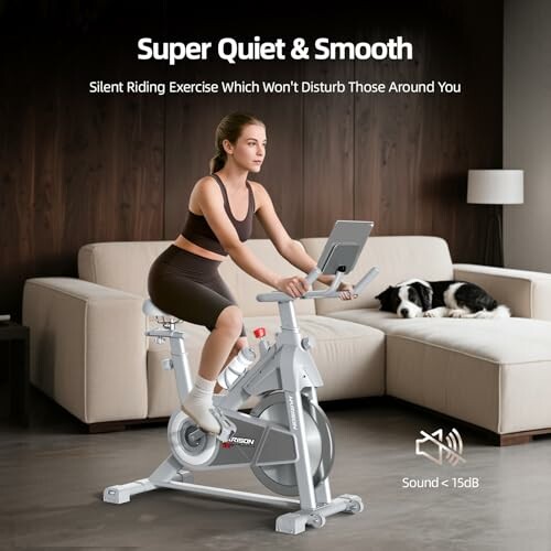 Woman exercising on a quiet stationary bike in a living room with a dog resting on the sofa.